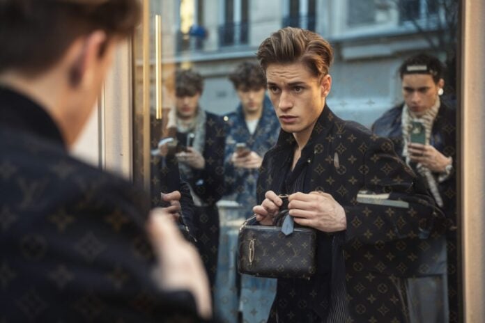 Mode masculine: le murse s'installe, coup marketing ou bascule durable des codes? Un homme hésite devant un miroir avec un sac masculin de luxe